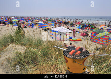 West Wittering, West Sussex, Regno Unito. 7 Luglio, 2013. Sizzling la domenica come giorno di gitanti prendere per il popolare West Wittering spiaggia per rinfrescarsi come le temperature sono aumentate a 30 gradi della navigazione nel sud dell Inghilterra seconda auto park aperto in grado di accogliere fino a 10.000 vetture. iphone e ipad sono stati presso il pronto per lo streaming del Wimbledon Tennis in spiaggia tende e sotto gli ombrelloni Foto Stock