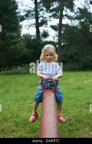 Bambino ragazza bionda che si divertono sull'altalena in un parco estate Foto Stock