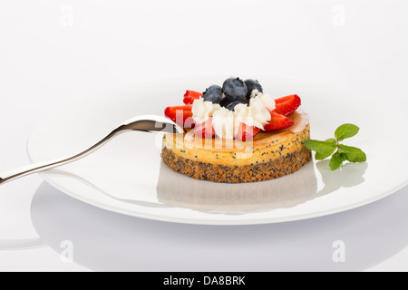 Cheesecake con mirtilli, fragole, menta e crema sulla piastra bianca. Foto Stock