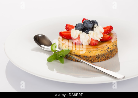 Cheese-cake con fragole, mirtilli, menta e crema sulla piastra bianca. Foto Stock