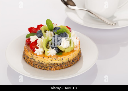 Cheesecake con fragole, mirtilli, kiwi e crema sulla piastra bianca. Foto Stock