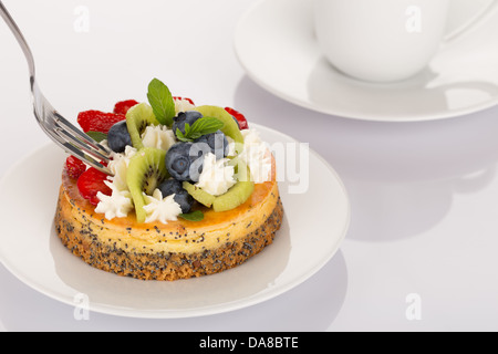 Cheese-cake con fragole, mirtilli, kiwi e crema sulla piastra bianca. Foto Stock