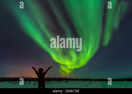 La donna sente gioia guardando l'aurora boreale (aurora borealis) da Churchill River sulla tundra fuori Churchill, Manitoba, MB, in Canada. Foto Stock