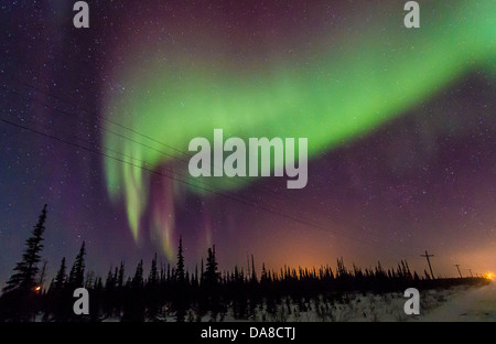 Northern lights visto da appena fuori Churchill, Manitoba in inverno. Luci della città può essere visto. Foto Stock