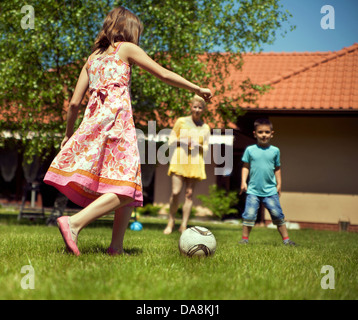 La famiglia felice giocando a calcio nel loro giardino Foto Stock