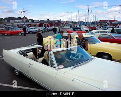 "Raggare" in stile rockabilly uomo di mezza età in un parcheggio con auto classiche di chattare con gli amici in una vecchia cabrio Foto Stock