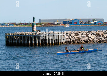 Barca a remi da studenti di club di canottaggio che passa la bottiglia di rosso Port Harbour luce di Tuborg Harbour, Copenhagen nord del porto Foto Stock