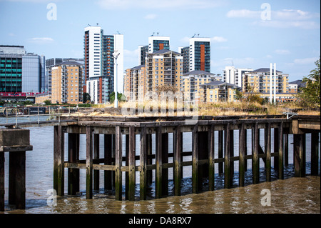 Moderni edifici sul lato nord del Tamigi a North Greenwich con pontile in disuso in primo piano sul lato sud Foto Stock