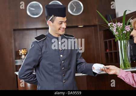 Gentile concergie in hotel dando una key card per senior donna Foto Stock