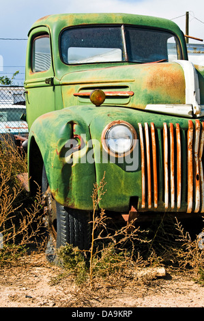 Un vecchio carrello in seduta a junkyard con erbacce che crescono intorno ad esso. Foto Stock