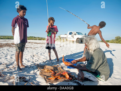 Guida aborigena Brian Lee e ragazzi indigeni a fuoco di campo dell'entroterra di Capo Leveque cottura granchio del fango Foto Stock