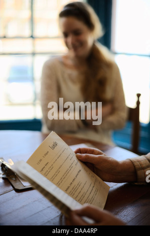 Giovane donna con sua nonna scegliendo da un menu nella finestra sedi in un ristorante a pranzo, Wales, Regno Unito Foto Stock