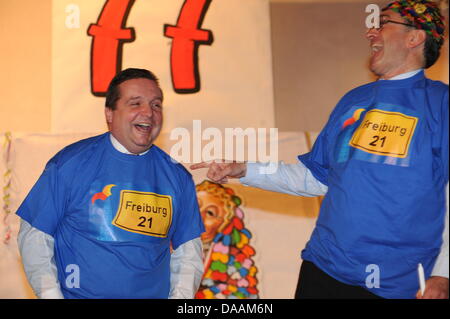 Freiburg direttivo dell'sindaco Dieter Salomon (R) e il Premier dello Stato del Baden Wuerttemberg, Stefan Mappus (CDU), ridere come Mappus riceve il carnevale onorario stolti hat aggiudicati da enti locali carnevale stolti guild a Friburgo in Germania il 5 febbraio 2011. Mappus è stata anche data una t-shirt che recita "Freiburg 21', un riferimento per il controverso progetto ferroviario 'Stuttgart 21'. Ph Foto Stock