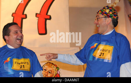 Freiburg direttivo dell'sindaco Dieter Salomon (R) e il Premier dello Stato del Baden Wuerttemberg, Stefan Mappus (CDU), ridere come Mappus riceve il carnevale onorario stolti hat aggiudicati da enti locali carnevale stolti guild a Friburgo in Germania il 5 febbraio 2011. Mappus è stata anche data una t-shirt che recita "Freiburg 21', un riferimento per il controverso progetto ferroviario 'Stuttgart 21'. Ph Foto Stock