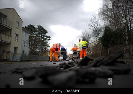 Il personale di una società roadmaking revisioni di danneggiare la superficie stradale di Dresda, in Germania, 08 febbraio 2011. Congelamento e scongelamento e rigide condizioni invernali causato danni alle superfici stradali in tutta la Germania. Foto: Arno Burgi Foto Stock