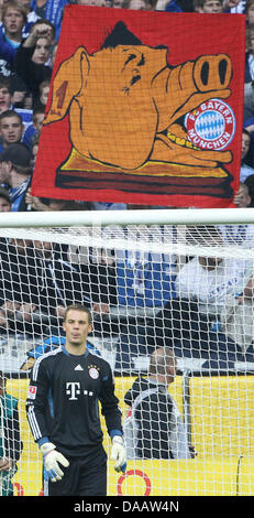 Monaco di Baviera è il portiere Manuel Neuer sorge nel suo obiettivo di fronte Schalke sostenitori tenendo un banner con un enorme maiale mangiare un logo Monaco di Baviera lui durante la Bundesliga tedesca partita FC Schalke 04 contro FC Bayern Monaco presso la VeltinsArena a Gelsenkirchen (Germania), 18 settembre 2011. Foto: Friso Gentsch Foto Stock