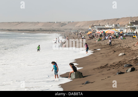 Persone nuotatori sulla sabbia spiaggia sabbiosa in Huanchaco, Perù. Foto Stock