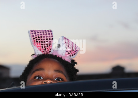 Baby girl peaking sebbene un tettuccio apribile al tramonto Foto Stock