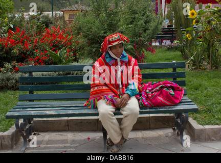 Ritratto di un peruviano uomo vestito con i tradizionali colorati poncho e cappello, seduti su una panchina nel parco,Ollantaytambo, Valle Sacra,Perù. Foto Stock