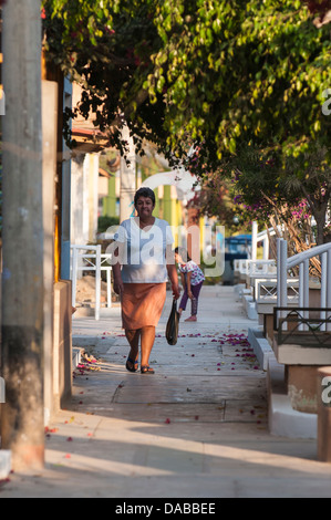 Donna che cammina sulla strada del centro scena di mancora, Perù. Foto Stock