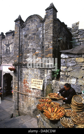 Un pescivendolo cinese che vende pesce salato e essiccato nell'insediamento Tujia del villaggio di Furong zhen una città vecchia elevata alla fama nel film di Hibiscus Città del 1986 situato nella contea di Yongshun, Prefettura di Xiangxi, provincia di Hunan Cina Foto Stock