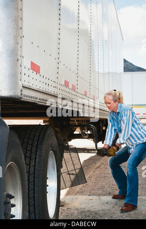 Donna bionda camionista aggancio di un rimorchio per il suo camion Foto Stock