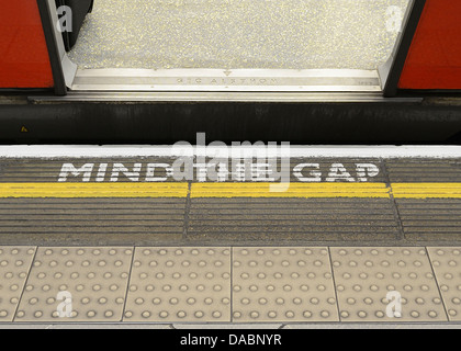 Mente il divario segno di avvertimento sul bordo della piattaforma di una stazione della metropolitana di Londra. Foto Stock