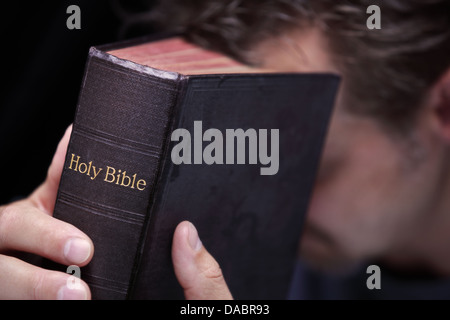 Mani giunte in preghiera attorno a Santa Bibbia Foto Stock