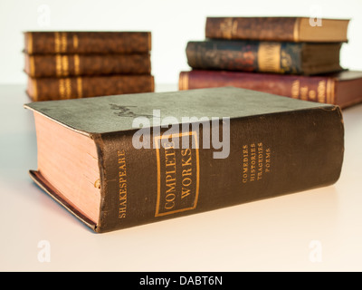 Una vecchia copia di le opere complete di Shakespeare con pile di vecchi libri al di fuori della messa a fuoco in background Foto Stock