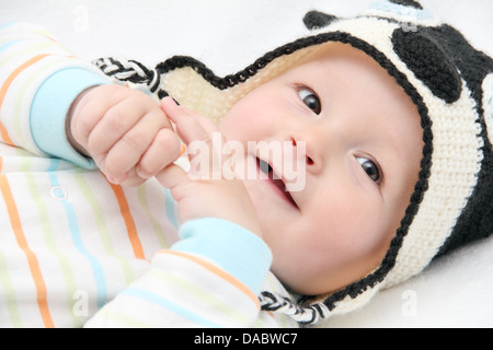 Sorridente baby giace sul retro sul letto bianco Foto Stock