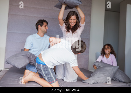 Famiglia avente una lotta di cuscini sul letto Foto Stock