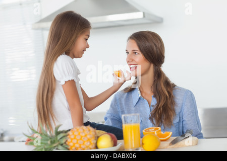 Bambina dando un segmento arancione a sua madre Foto Stock