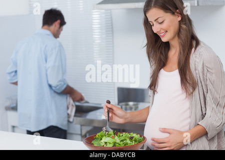 Donna incinta la miscelazione di un insalata in cucina Foto Stock