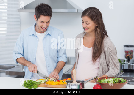 Uomo di funghi di trinciatura accanto al suo partner in stato di gravidanza Foto Stock