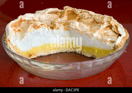 Home reso Lemon Meringue Pie in recipiente di vetro rosso sul piano di lavoro Foto Stock