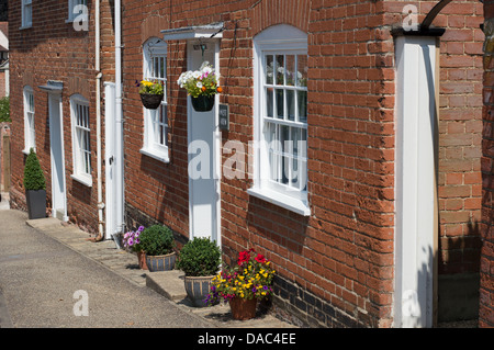 Nei cestini appesi e altre piante adornano la parte anteriore del case a schiera in Kersey, Suffolk, Inghilterra. Foto Stock