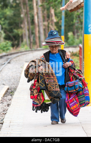 Venditore Souvenir con tessuti in attesa del treno di trasporto auto a Ollantaytambo stazione dei treni di Ollantaytambo, Valle Sacra, Perù. Foto Stock