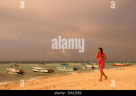 Donna che parla al cellulare e passeggiate sulla spiaggia a Playa del Carmen e Riviera Maya, Messico. Foto Stock