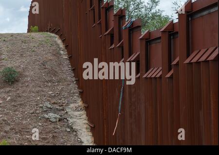 Luglio 10, 2013 - Nogales, Arizona, Stati Uniti - una corda di fortuna fatta di cinghie cargo legati insieme pende dal la recinzione di confine vicino a Nogales, in Arizona. I funzionari dicono che semplicemente salendo la recinzione di confine è ancora un popolare mezzo di entrare negli Stati Uniti per entrambi contrabbandieri e migranti. (Credito Immagine: © sarà Seberger/ZUMAPRESS.com) Foto Stock