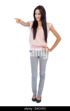 Sorridente giovane donna rivolti a qualcosa Foto Stock