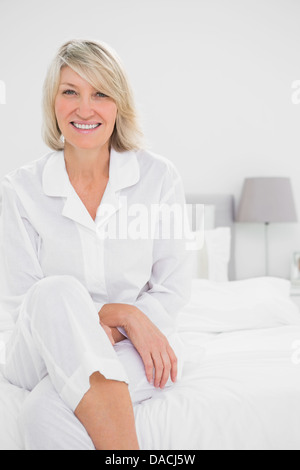 Donna bionda seduta zampe trasversale nella sua camera da letto Foto Stock