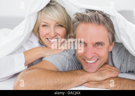 Coppia sorridente sotto i coperchi Foto Stock