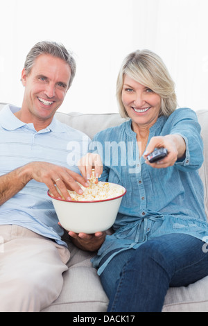 Paio di guardare la tv e mangiare popcorn sul divano Foto Stock