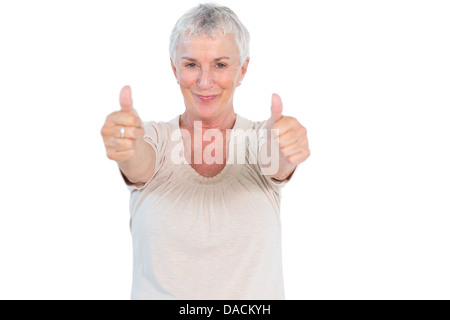Donna matura sorridente in telecamera dando pollice in alto Foto Stock