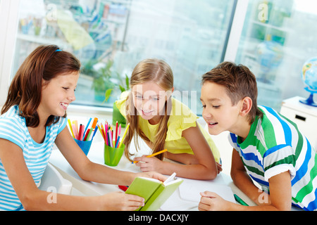 Compagni di classe essendo curiosi di sapere che cosa i loro simpatico amico lettura Foto Stock