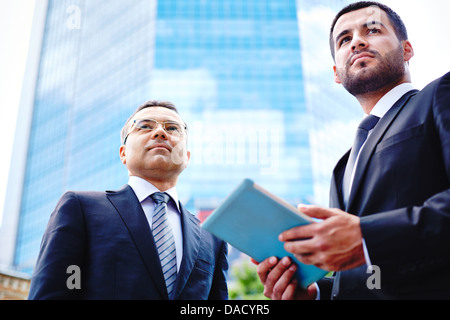 Immagine dei due ragazzi di business in ambiente urbano, il più giovane azienda un touchpad Foto Stock