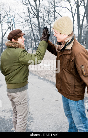 Due giovani uomini riuniti in winter park dando alta cinque Foto Stock