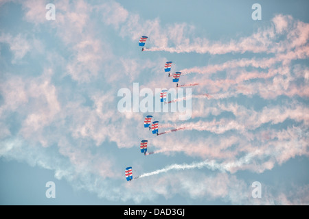 Skydivers dalla Royal Air Force Falcons team display riempiono il cielo con i loro paracadute colorato tettoie e sentieri di fumo. Foto Stock