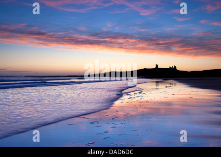 Attraverso Embleton Bay a sunrise verso le rovine del castello di Dunstanburgh, Embleton, nelle vicinanze Alnwick, Northumberland, England, Regno Unito Foto Stock