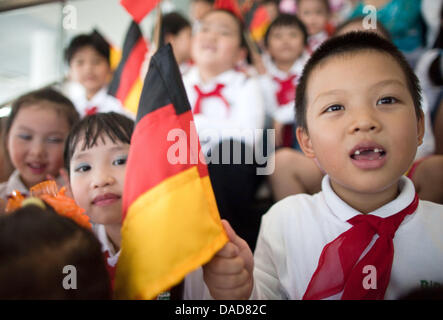 Un ragazzo vietnamita detiene una bandiera tedesca guida turistica mentre il Cancelliere tedesco Angela Merkel assiste l'apertura di una fabbrica di tecnologia medica fabbricante B. Braun ad Hanoi, Vietnam, 11 ottobre 2011. Incontro tra il primo ministro Tan Dzung, Merkel intende visitare le aziende economiche durante la sua visita ufficiale. Foto: MICHAEL KAPPELER Foto Stock